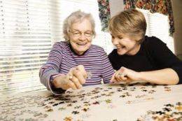 oudere vrouw naast jongere vrouw samen puzzelen