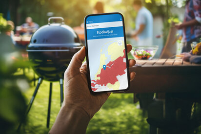 hand met telefoon waarop stookwijzer is geopend