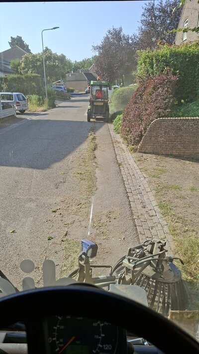 De weg wordt geveegd met de veegwagen en onkruid wordt verwijderd